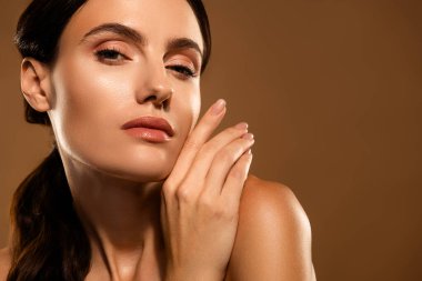 Temiz, parlak ciltli, doğal güzelliği ve özeni vurgulayan güzel bir kadının yakın plan görüntüsü. Tarafsız arka plan, sıcak tonların ve yumuşak özelliklerin altını çizerek zarif ve rahatlatıcı bir atmosfer yaratıyor..