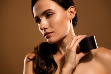 Güzel bir genç kadın, pürüzsüz bir ten ve cilt ürününü güzellik temalı promosyon görüntüsünde sergiliyor.