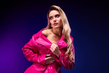 Pembe ceketli zarif bir kadın model. Mor bir arka planda canlı bir şekilde sergilenen özgüven ve entelektüellik yayıyor..