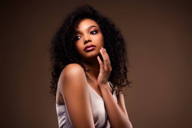 Kendine güvenen, zarif bir kıyafet giyen ve yumuşak kahverengi bir arka plana sahip genç bir kadının çarpıcı bir portresi. İnce güzelliği zarif ve sofistike kompozisyonu tamamlıyor..