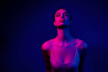 Büyüleyici bir görüntü. Canlı neon, pembe ve mavi ışıklı genç bir kadın. Çok güzel ve zarif.