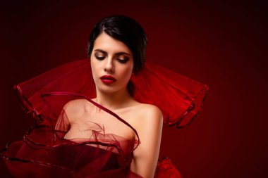 Şık esmer, göz kamaştırıcı bir güzellik, canlı makyajlı, zarif, sofistike ve alımlı, lüks, kırmızı bir arka plana karşı..