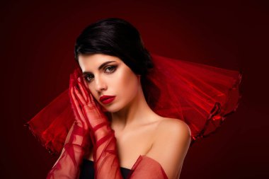 Kırmızı katıksız giyinmiş şık esmer bir kadın zengin kırmızı bir arka plana karşı poz veriyor, zarafet ve şehveti ifade ediyor..