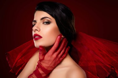 Güzel esmer kadın kırmızı eldiven ve göz kamaştırıcı makyaj, zarafet ve cazibe yayıyor, lüks bir arkaplan ile çevrili.