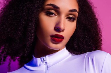 Göz alıcı makyajı, canlı ışıklandırması, modern tarzı ve zarif cazibesi olan güzel bir genç kadının yakın çekimi..