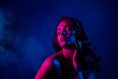 Canlı neon ışıkların altında poz veren genç bir kadın model, parti atmosferiyle güzellik, tarz ve kendine güven sergiliyor..