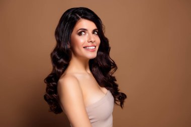 Genç, esmer bir kadın zarif, zarif, kadınsı, dalgalı saçlı, parlak tenli profesyonel ve sanatsal kavramlar için tarafsız bir arkaplan kullanıyor..