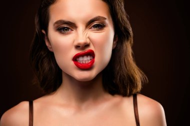 Koyu kırmızı rujlu esmer bir kadın ve koyu bir arka plana karşı duran kendine güvenen bir ifade..