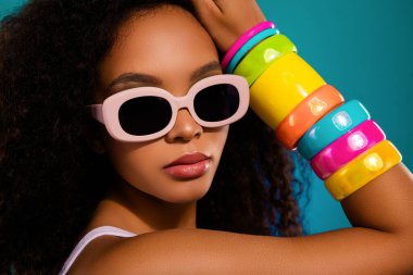 Afro saç stili, retro güneş gözlüğü ve renkli bilezikleri olan şık stili ve modern trendleri olan şık bir genç kadının portresi..