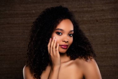 Doğal ve kendine güvenen zarif bir genç kadın. Büyüleyici ve kusursuz makyajı çarpıcı güzelliği, dengeli bir kompozisyon oluşturmak için desenli kahverengi arkaplan ile uyumlu..