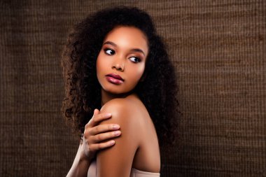 Zarif poz veren zarif bir genç kadının sofistike görüntüsü. Güzel kıvırcık saçlarını, ışıl ışıl tenini ve şık görünümünü ön plana çıkarıyor..