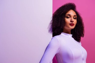 Cesur pembe ve mor bir zemin önünde özgüvenle poz veren zarif genç kadın, vurgulama tarzı ve modernlik