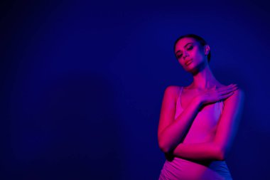 Canlı neon, pembe ve mavi ışıkla aydınlatılmış zarif genç bir kadın güven ve cazibe sergiliyor. Gece hayatı, stil ve fütüristik estetik temalar için mükemmel..