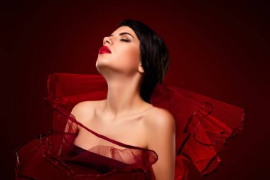 Parlak kırmızı bir elbise giyen şık bir esmer güzelliğini ve tarzını sergiliyor, cazibe ve moda kavramları için ideal..