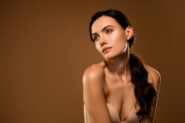 Genç esmer kadın zarafet ve sadelik sergiliyor. Parlak cildi ve şık saç stiliyle kadınsı bir duruş sergiliyor..