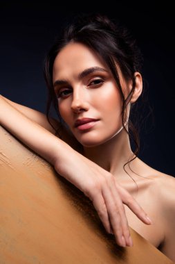 Kusursuz makyajlı, parlak tenli, etkileyici duruşu olan, zarafet ve güzelliği vurgulayan genç bir kadının yakın plan sanatsal portresi.