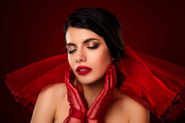 Kırmızı makyajlı ve uyumlu eldivenleri olan esmer kadın, güzellik ve zarafeti vurgulayan, kırmızı peçeli ve değişken arkaplanlı.