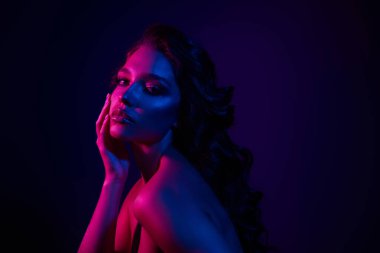 Neon ışıklı genç bir kadının sanatsal görüntüsü gösteriş tarzı ve cazibesi. Şık ve dramatik bir atmosferde canlı renkler güzellik ve duyguları vurgular..