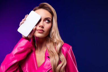 Pembe trençkotlu zarif bir bayan model akıllı bir telefon tutuyor, anlamlı bir mor gradyan üzerinde poz veriyor..