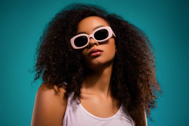 Güneş gözlüklü, modaya uygun bir kadının portresi, modern pop-kültür temasında gençlik ve dinamik enerjiyi ifade eden renkli bir arka plana karşı gösteriş tarzı, zarafet ve güzellik..