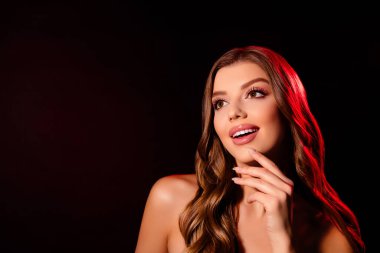 Parlak kozmetik eşli, şık, çekici bir kadının fotoğrafı ruj sürme, çene dokunma, koyu renkli arka plan..