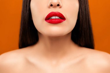 Kalın kırmızı rujla süslenmiş, parlak turuncu bir arka plana şehvet ve şehvet saçan bir kadın dudaklarının şık yakın plan görüntüsü..