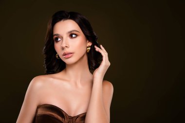 Moda fotoğrafçılığı için lüks bir korsenin içinde zarif pozlar veren altın küpelerle süslenmiş genç bir kadın manken.