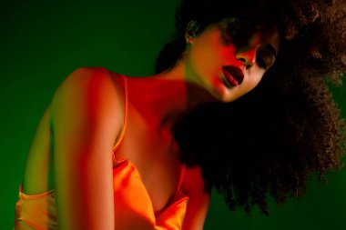 Şehvetli kıvırcık saçlı, şık bir genç kadın. Parlak ışık altında güzelliğini ve tarzını ön plana çıkarıyor. Görüntü, çağdaş yaklaşımıyla cazibe, şehvet ve entelektüellik yayar..