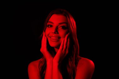 Yumuşak ten yanaklarına dokunan muhteşem modelin fotoğrafı tende izole edilmiş çok renkli gece kulübü kırmızı neon ışıklı siyah arka plan.