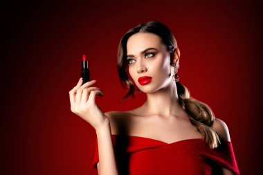 Zarif genç esmer kadın elinde canlı kırmızı ruj sergiliyor, güzelliği, cazibeyi ve şıklığı vurguluyor, lüks etkinlikler ve kutlamalar için mükemmel..