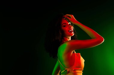 Şık ışıklandırmalı kendine güvenen, şık bir elbise giyen genç bir kadın. Gösteride lüks ve cazibe vurgulanıyor, şık partiler ve etkinlikler için mükemmel..