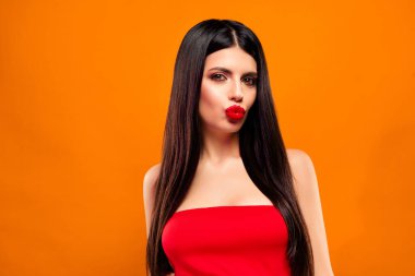 Uzun koyu renk saçlı, parlak makyajlı, şık kırmızı bluzlu, parlak turuncu arka plan, somut cazibe, entelektüellik ve canlı, çağdaş bir titreşim karşısında yaratıcı bir şekilde poz veren genç bir manken..