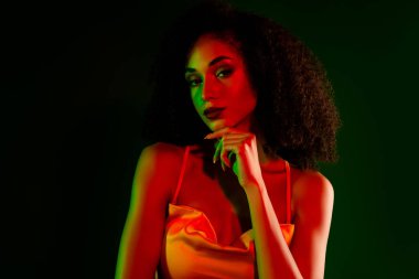 Zarif bir tarzı olan zarif genç bir kadın, renkli bir arkaplanda poz veriyor. Şık ve modaya uygun bir hava, güzelliği, zarafeti ve sofistikeliği vurguluyor.