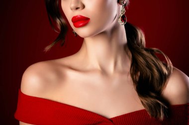 Kırmızı, omuz üstü bir elbise giyen, zarif küpeler takan, göz alıcı makyaj yapan, lüks, zarif ve kendine güvenen çekici bir kadın..