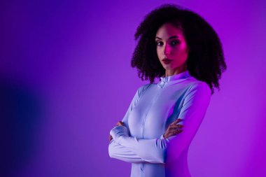 Şık bir genç kadın, parlak neon ışıkların altında, dinamik bir atmosferde modern güzelliğin ve çağdaş modanın altını çizerek güven içinde poz verir..