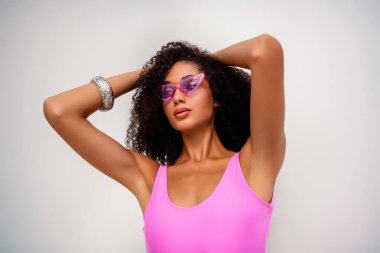 Şık giyinen, sade bir arka plana özgüvenle poz veren, modern zarafet ve canlı kişiliğe sahip genç bir kadının göz alıcı portresi.