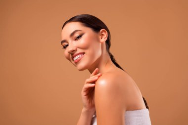 Parlak tenli esmer kadın, bej arkaplanda poz veriyor, zarafeti, güzelliği ve doğal ten rengini vurguluyor, cilt ve spa kavramları için..