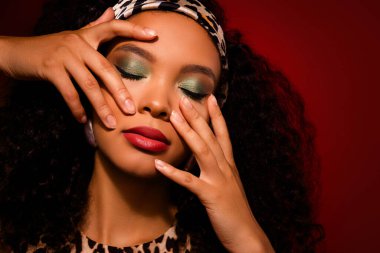 Sanatsal makyajlı, leopar desenli ve kıvırcık saçlı, kendine güvenen ve şık bir poz veren güzel bir kadının yakın çekimi. Güzellik, moda ve tensel kavramsal temalar için mükemmel..