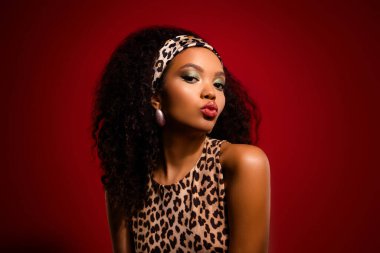 Leopar desenli giyinen ve kendine güveni tam bir şekilde poz veren göz kamaştırıcı genç bir kadın..