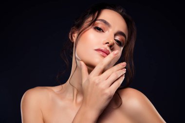 Büyüleyici bir ifadeye sahip çarpıcı genç bir kadın manken, kusursuz bir güzellik, zarif bir makyaj, şekilli saçlar, ve koyu bir arkaplanda parlak bir ten..