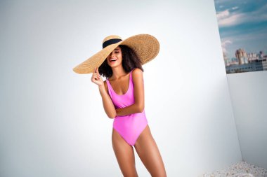 Zarif yaz kıyafetleri içinde kendine güvenen, pembe mayosu ve güneş şapkası olan, açık havanın tadını çıkaran, cazibe ve tarz sahibi genç bir kadın..