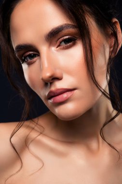 Büyüleyici bir portre, kusursuz bir cilde ve zarif makyaja sahip, koyu bir arkaplana karşı zarafet ve cazibeyi vurgulayan genç ve güzel bir kadını gözler önüne seriyor..