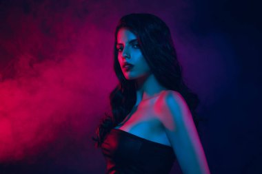 Stylish and elegant young woman posing in neon light with vibrant pink and blue tones and dramatic smoky background, symbolizing nightlife, glamour, and fashion imagery.