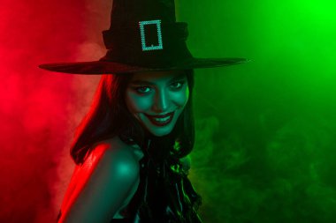 A captivating woman dressed as a witch in an enchanting Halloween atmosphere filled with vibrant lighting and mystery.