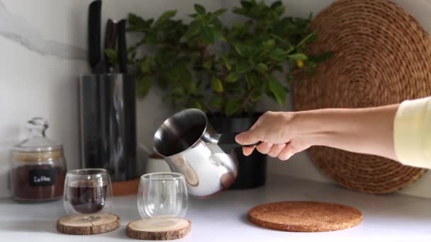 女性の手がタークからグラスカップに新鮮なコーヒーを注ぐ 朝食コーヒーのコンセプト 自宅でコーヒーを作るプロセス 4K映像 — ストック動画