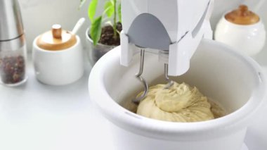 Karıştırıcı hamuru çevirme kabında karıştırıyor. Kaseli sabit bir mikser hamuru ağır çekimde yoğurur..
