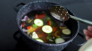 Vegetables are boiled in a casserole. Vegetables spin around in a pot with hot water. The concept of vegetarianism and healthy organic food.