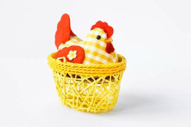 Decorative chicken in a yellow wicker basket on a white isolated background with space for text. Easter card Provence. Easter composition.