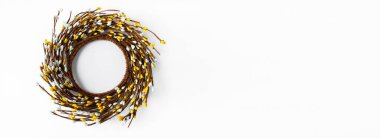Banner of minimal Easter composition with place for text. Concept of creative arrangement made of blossoming twigs. Handcraft Easter wreath made from twigs isolated on white background.