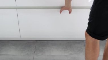 Genç bir adam mutfaktaki konteynırlarda çöpleri ayırıyor. Atık ayıklama sistemi olan modern bir mutfak. Atık Ayrım Konsepti. Sıfır kayıp. Çevre dostu. 4K görüntü.